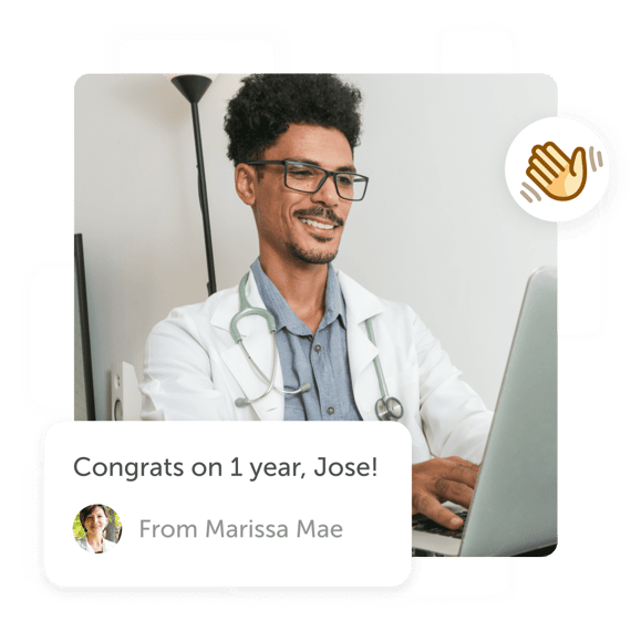 Doctor smiling looking at "congrats on 1 year" post on laptop